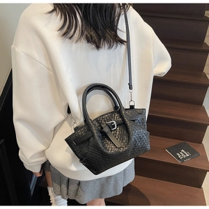 Détail du sac seau noir tissé à la main avec boucle argentée et bandoulière réglable