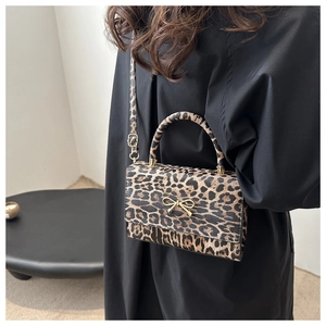 Detailed side view of leopard print crossbody bag with golden bow clasp and strap