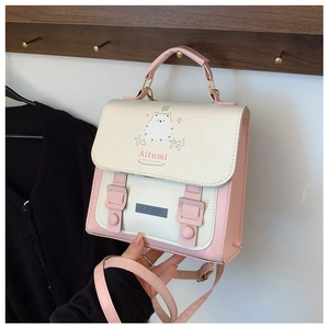 Detail view of pink and beige mini satchel featuring cartoon Samoyed print on wooden rack