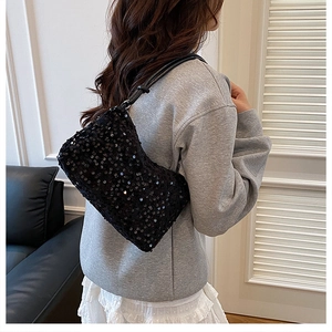 Detail of black sequined shoulder bag with leather strap shown in a modern interior setting