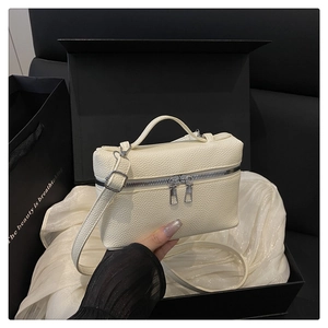 Detail of off-white lychee texture leather crossbody bag with dual silver metal zippers