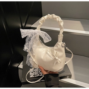 Detail of white ruched shoulder bag with large lace bow and elegant leather accents