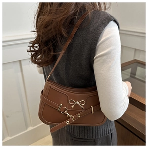 Détail d'un sac bandoulière en similicuir marron foncé avec nœud doré et boucle rétro