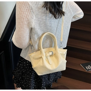 Détail d'un sac seau tissé blanc cassé avec bandoulière sur un mannequin