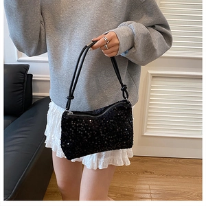 Close-up of a black sequin pillow bag with silver zipper and slim shoulder straps