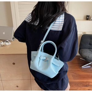 Détail du sac à bandoulière bleu clair à texture tissée avec fermoir métallique