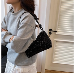 Close-up of black sequined shoulder bag featuring leather knotted strap and metal zipper