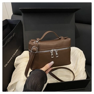 Detail of brown litchi pattern leather crossbody bag with silver hardware and top handle