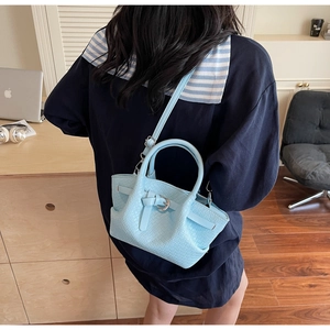 Détail du sac seau bleu clair avec texture tissée et lanière décorative à boucle métal
