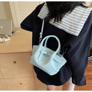 Détail d'un sac bandoulière bleu clair à motif crocodile porté par un mannequin au bureau