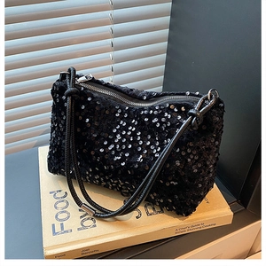 Detailed view of black sequin handbag resting on a book with soft window light shadows