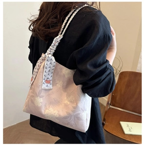 Détail d'un sac à fleurs rose avec bandoulière tissée et foulard sur un mannequin