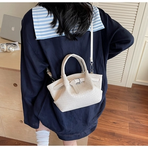 Détail du sac seau tressé beige avec boucle métallique sur la bandoulière décontractée