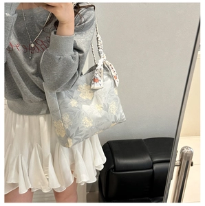 Détail du sac cabas floral bleu clair avec foulard à motifs noué sur l'anse