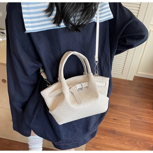 Détail d'un sac seau en cuir tressé crème avec boucle décorative et ferrures métalliques