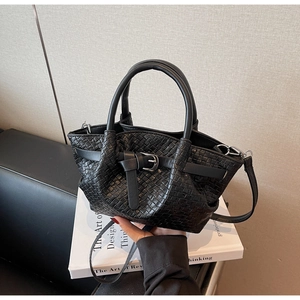 Détail du sac seau noir tissé à la main avec boucle argentée et texture quadrillée chic