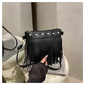 Détail d'un sac bandoulière noir à franges avec des clous argentés sur un support