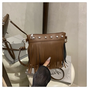 Détail d'un sac bandoulière marron en similicuir avec clous argentés et longues franges