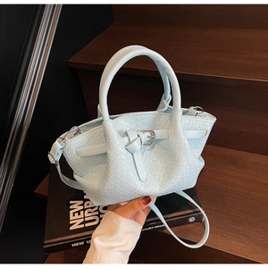 Détail du sac seau bleu clair avec texture tressée et boucle de ceinture nouée