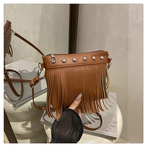 Détail d'un sac bandoulière en similicuir marron avec de longues franges et des rivets