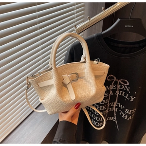 Détail du sac à main beige tressé avec boucle métallique et finitions de poignée supérieure