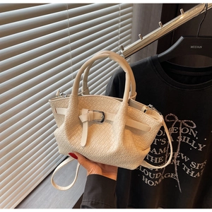 Détail de la texture tressée du sac seau crème avec boucle argentée et bandoulière