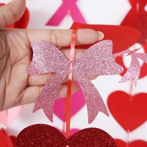 Close-up of pink glitter bow and red heart hanging decorations for Valentine's Day party