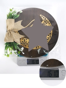 Detail of wooden moon star plaque with burlap bow and greenery on an electronic scale