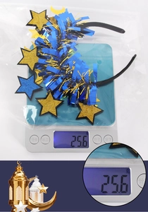 Star and moon headband with blue tinsel and glitter stars on a scale showing 25.6g weight