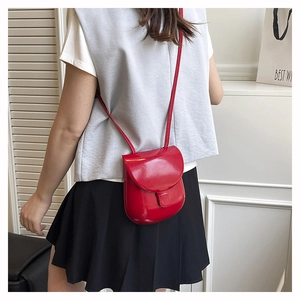 Model view of a red patent leather mini crossbody bag with a glossy finish and thin strap