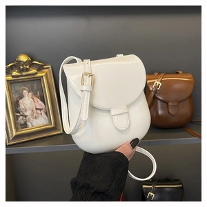 Close-up of white minimalist saddle bag with polished leather and gold square buckle