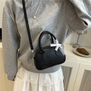 Minimalist black Boston handbag with embossed text and white lace bow on shoulder bag