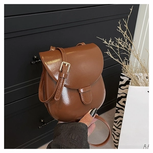 Detail of a brown vintage saddle bag with glossy smooth leather and metal buckle strap