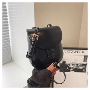Detail of black PU leather mini shoulder bag with flap design and gold metal buckle