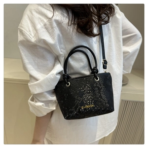 Detail of black snake pattern mini bucket bag with gold lettering and top handle