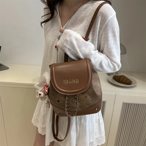 Mini sac à dos marron avec chaîne et breloque ours porté par un mannequin élégant