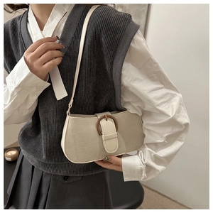 Detail of a beige minimalist underarm bag featuring a bronze metal ring buckle and wide strap