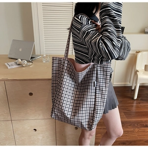 Close-up of black and white checkered canvas tote bag with soft pink lining detail