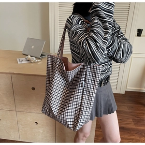 Detail view of checkered tote bag with large capacity and pink lining on office desk