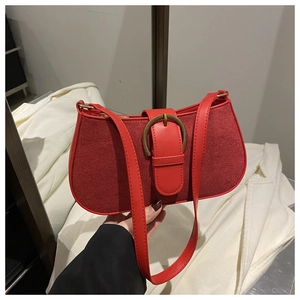 Close-up of red suede and leather shoulder bag with a gold metal horseshoe buckle