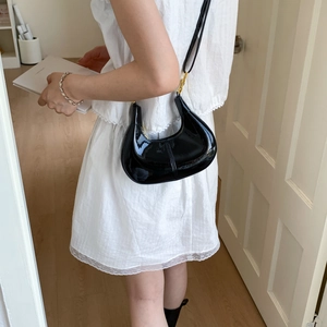 Minimalist black patent leather crescent shoulder bag with golden metal hardware