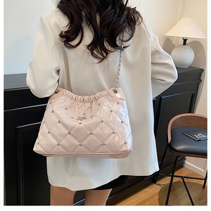 Detail of pink quilted chain bag with star plaque and stud accents worn by model