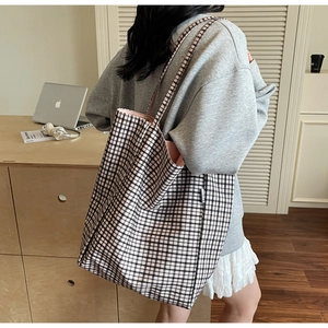 Close-up of black and white checkered canvas tote bag with side label and pink lining