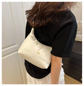 Gros plan d'un sac à bandoulière blanc crème avec texture serpent et logo doré