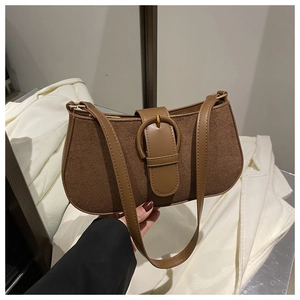 Detail of brown baguette bag with leather stitching and a metallic decorative buckle