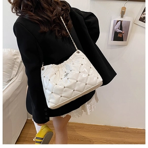 Detail of white quilted leather shoulder bag with silver chain and rivet accents