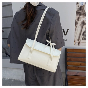 Close-up of creamy white shoulder bag with decorative bow and premium leather texture