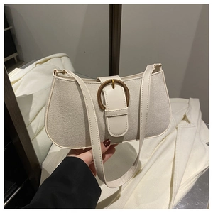 Detail of cream crossbody bag featuring textured fabric and vintage gold buckle closure