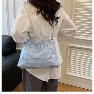 Close-up of light blue quilted patent leather bag with silver star logo and chain strap