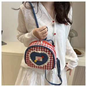 Detail of red checkered canvas bag featuring heart embroidery and lace trim on a white strap